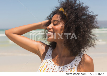 Young African American woman with hands in hair standing on the beach Young African American woman with hands in hair standing on the beach 53004644