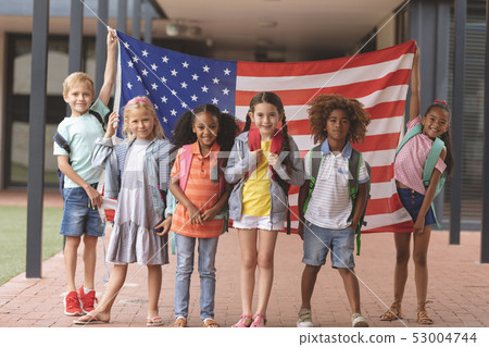 Happy school students standing in corridor while holding american flag Happy school students standing in corridor while holding american flag 53004744