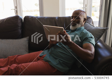 Senior man using digital tablet in living room 53004745