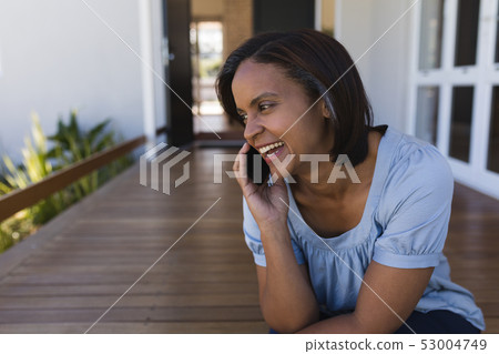 Woman talking on mobile phone on the porch at home 53004749