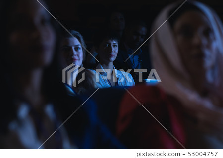 Businesswoman holding laptop and listening to the presentation in auditorium 53004757