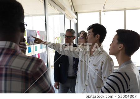 Business colleagues discussing over chart in office Business colleagues discussing over chart in office 53004807