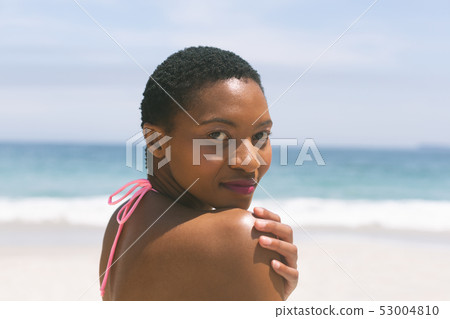 Woman standing on beach on a sunny day Woman standing on beach on a sunny day 53004810