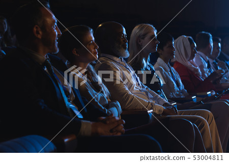 Business colleagues sitting and watching presentation with audience Business colleagues sitting and watching presentation with audience 53004811