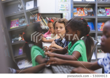 Happy schoolboy sitting in computer room  53004913