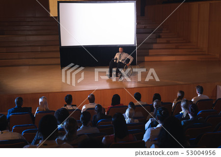 Businessman sitting on a wheelchair and giving presentation to the audience  53004956