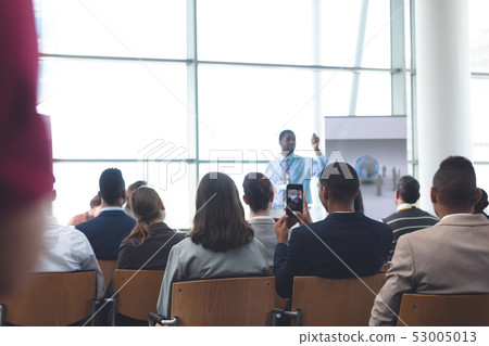 Businessman clicking photo with mobile phone in a business seminar Businessman clicking photo with mobile phone in a business seminar 53005013