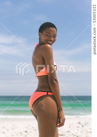 Woman posing while standing on beach on a sunny day Woman posing while standing on beach on a sunny day 53005333