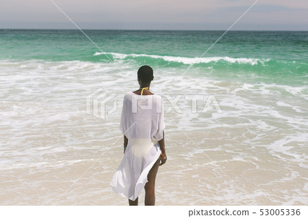 Woman relaxing and standing on beach  53005336