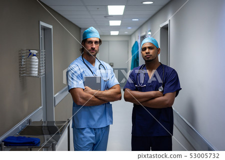 Male surgeons standing at hospital corridor Male surgeons standing at hospital corridor 53005732