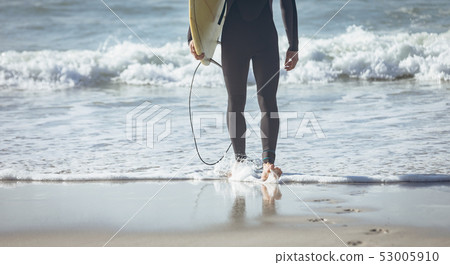 Male surfer with a surfboard walking on a beach 53005910