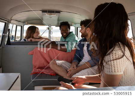 Group of friends interacting with each others in camper van at beach Group of friends interacting with each others in camper van at beach 53005915