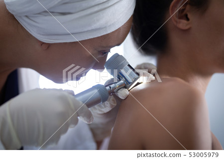 Female doctor checking woman body with dermatoscopy 53005979