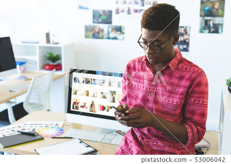 Graphic designer using mobile phone at desk in office Graphic designer using mobile phone at desk in office 53006042