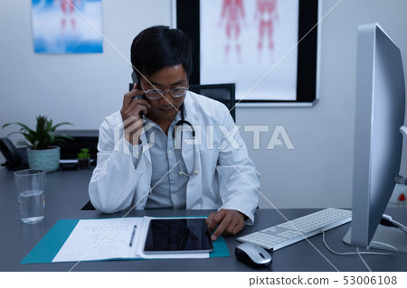 Doctor talking on mobile phone while using digital tablet Doctor talking on mobile phone while using digital tablet 53006108
