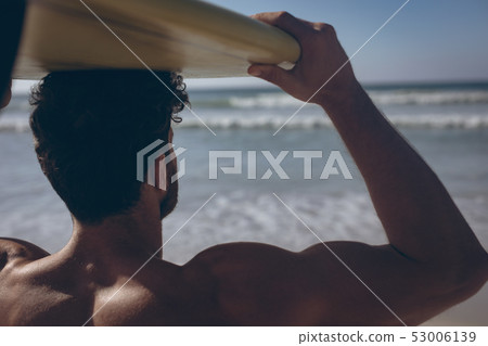 Male surfer carrying his surfboard at beach 53006139
