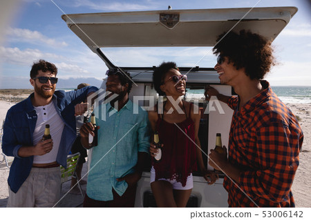 Group of friends enjoying at beach while standing near camper van Group of friends enjoying at beach while standing near camper van 53006142