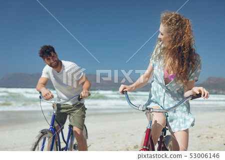 Happy couple riding bicycle at beach on a sunny day 53006146