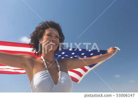 Woman holding american flag at beach 53006147