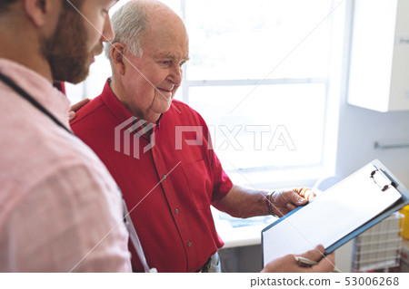 Male doctor showing medical report to senior patient 53006268