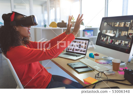 Female graphic designer using virtual reality headset at desk  53006348