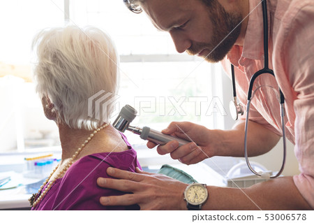 Male dermatologist examining senior patient through dermatoscopy 53006578