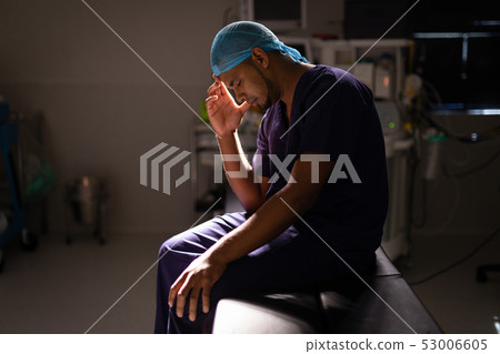 Nervous male surgeon sitting in operation room at hospital Nervous male surgeon sitting in operation room at hospital 53006605