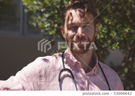 Confident male doctor sitting on bench outside the nursing home Confident male doctor sitting on bench outside the nursing home 53006642