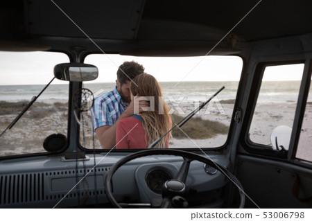 Inside view of a camper van of a Caucasian couple hugging each other against ocean in background Inside view of a camper van of a Caucasian couple hugging each other against ocean in background 53006798