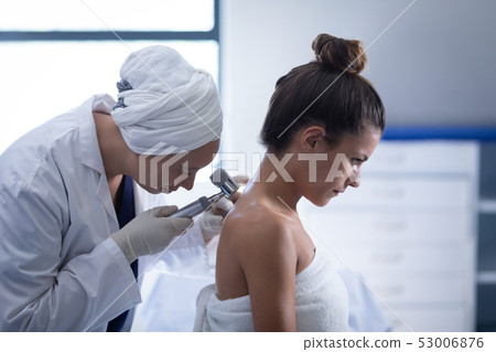 Female doctor checking patient with dermatoscopy Female doctor checking patient with dermatoscopy 53006876
