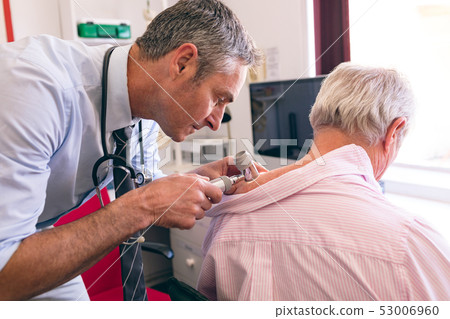 Male dermatologist examining senior patient with dermatoscopy 53006960