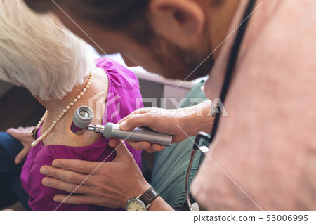 Male dermatologist examining senior patient through dermatoscopy Male dermatologist examining senior patient through dermatoscopy 53006995