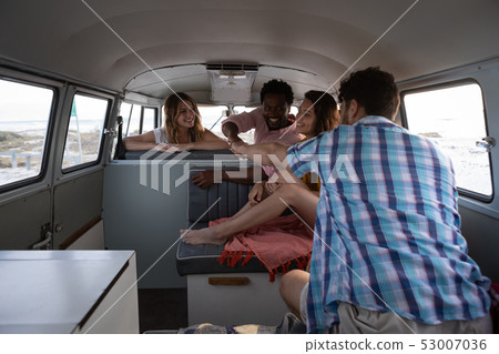 Group of friends giving fist bump in camper van at beach 53007036