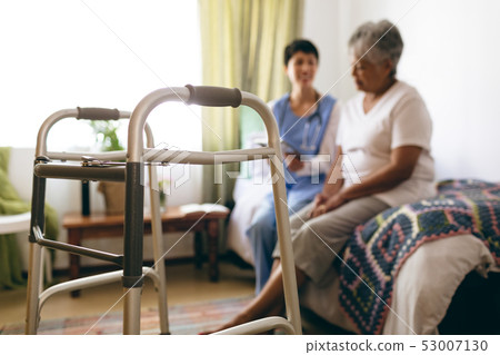 Female doctor interacting with senior female patient at retirement home 53007130