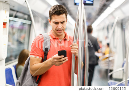 Male is traveling and standing with mobile in the train Male is traveling and standing with mobile in the train 53009135