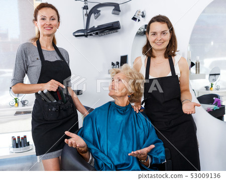 Hairstylists presenting result of styling to female client 53009136