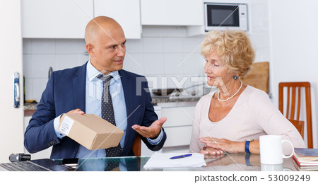 Sales representative passing box to woman Sales representative passing box to woman 53009249