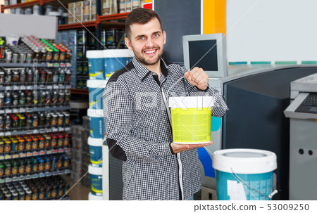 Man holding bucket of paint in store Man holding bucket of paint in store 53009250