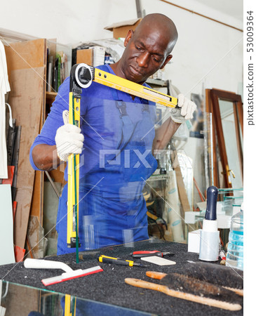 glass factory worker measuring glass with angle finder level before cutting glass factory worker measuring glass with angle finder level before cutting 53009364