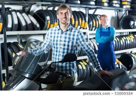 Cheerful man customer holding his motorcycle 53009384