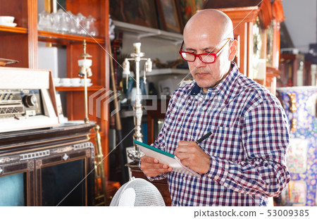 Man making notes in antique store 53009385