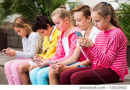 Children playing on smartphone outdoors 53010002