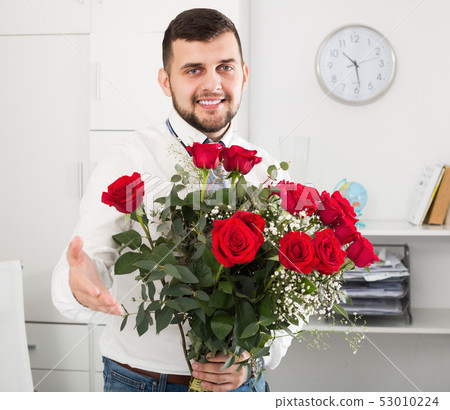 Smiling young male presenting bouquet of flowers Smiling young male presenting bouquet of flowers 53010224