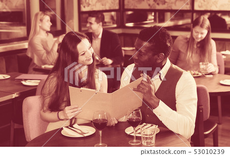 Happy couple discussing restaurant menu 53010239