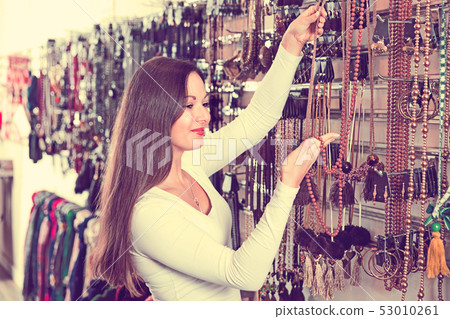 Cheerful young female choosing different pendants in the jewelry store Cheerful young female choosing different pendants in the jewelry store 53010261