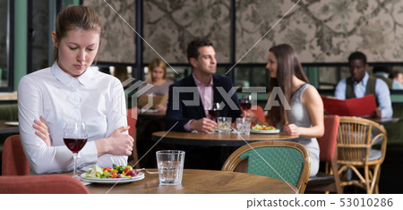 Upset girl dining alone in restaurant 53010286