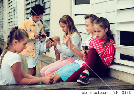 Five kidsare chatting on their smartphone Five kidsare chatting on their smartphone 53010338