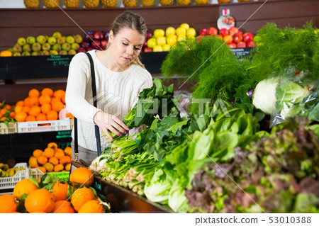 Female customer choosing greens and letuce on the supermarket Female customer choosing greens and letuce on the supermarket 53010388