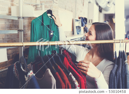 Portrait of pretty woman customer choosing shirt 53010458