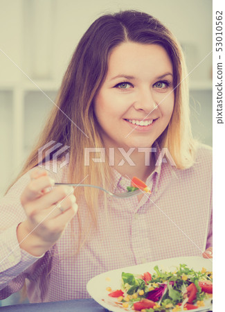 Girl eating green salad 53010562